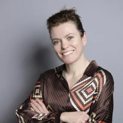 Femme souriante en chemise à motifs géométriques, bras croisés