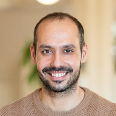 Homme souriant avec barbe portant un pull beige